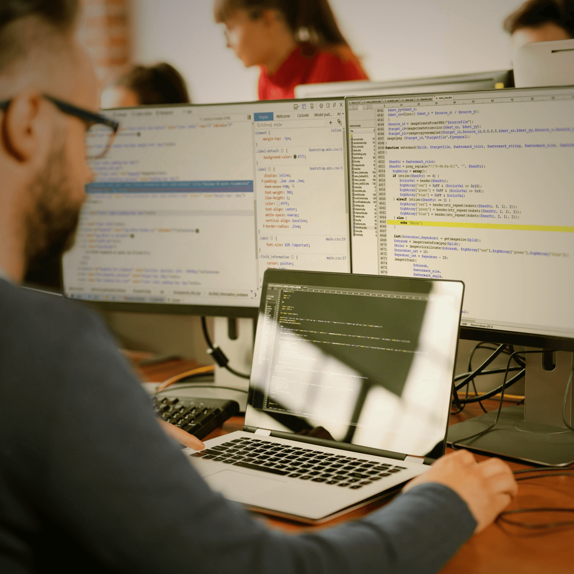 Employee works on notebook with two other screens. Development of programming and coding technologies.