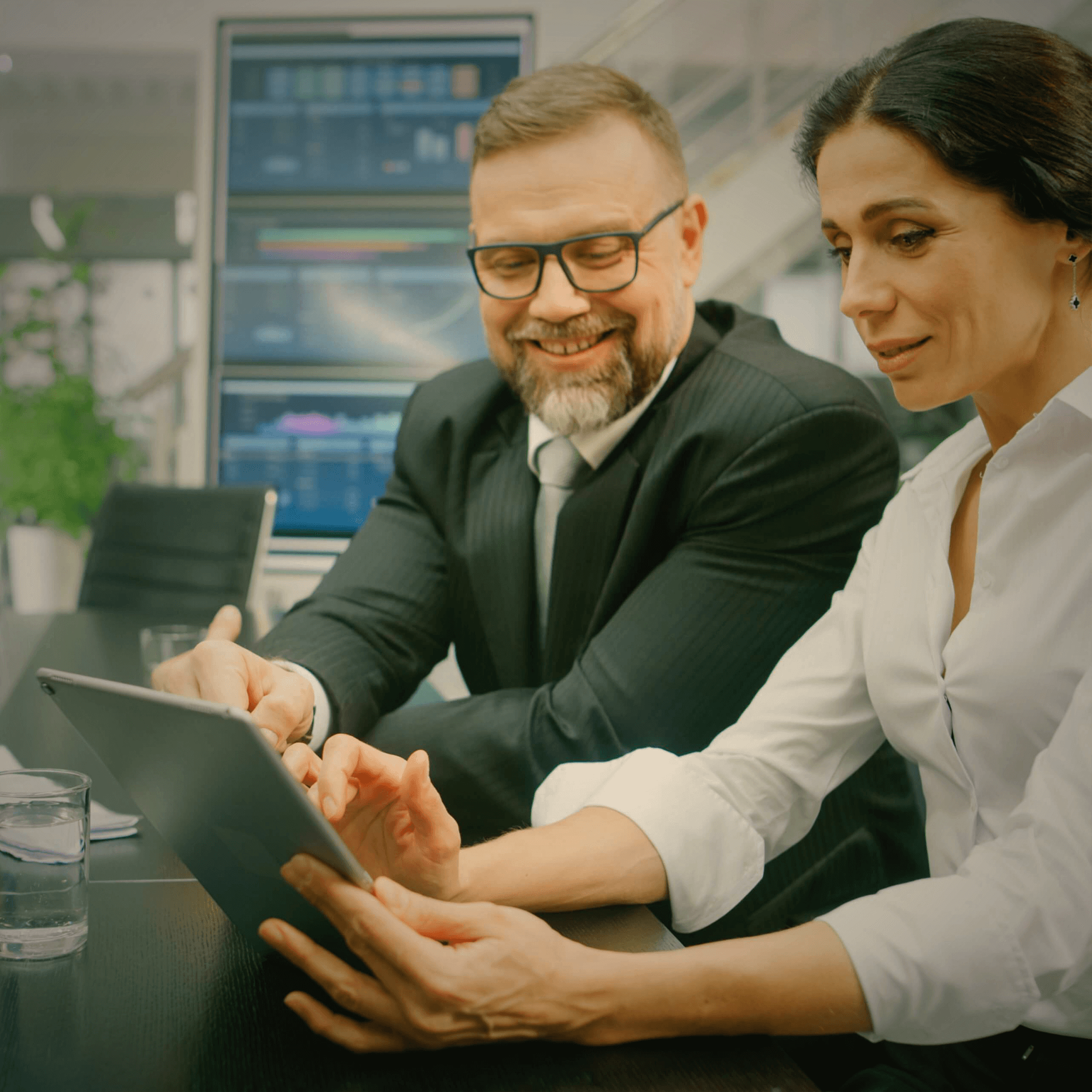 In the meeting room, the female executive shows the male investor a digital tablet computer.