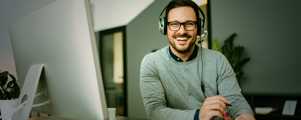 Supportmitarbeiter bearbeitet einen Kundenfall vor einem Notebook mit einem Headset auf dem Kopf