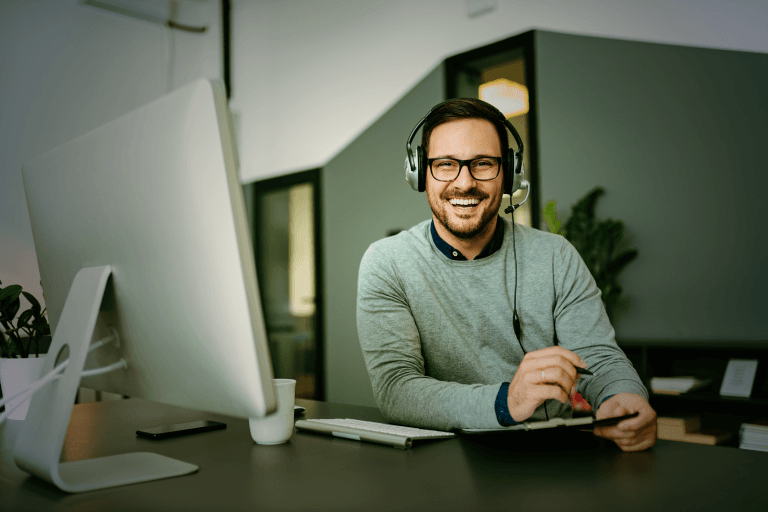 Supportmitarbeiter bearbeitet einen Kundenfall vor einem Notebook mit einem Headset auf dem Kopf